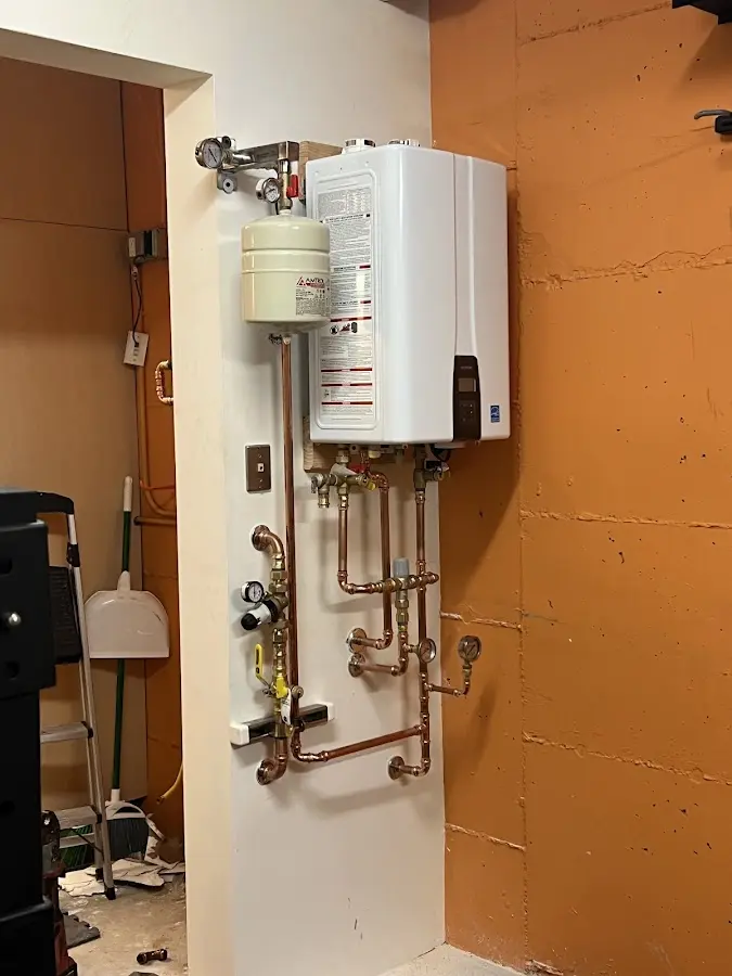 Plumbing technician inspecting water heater connections in Lochearn